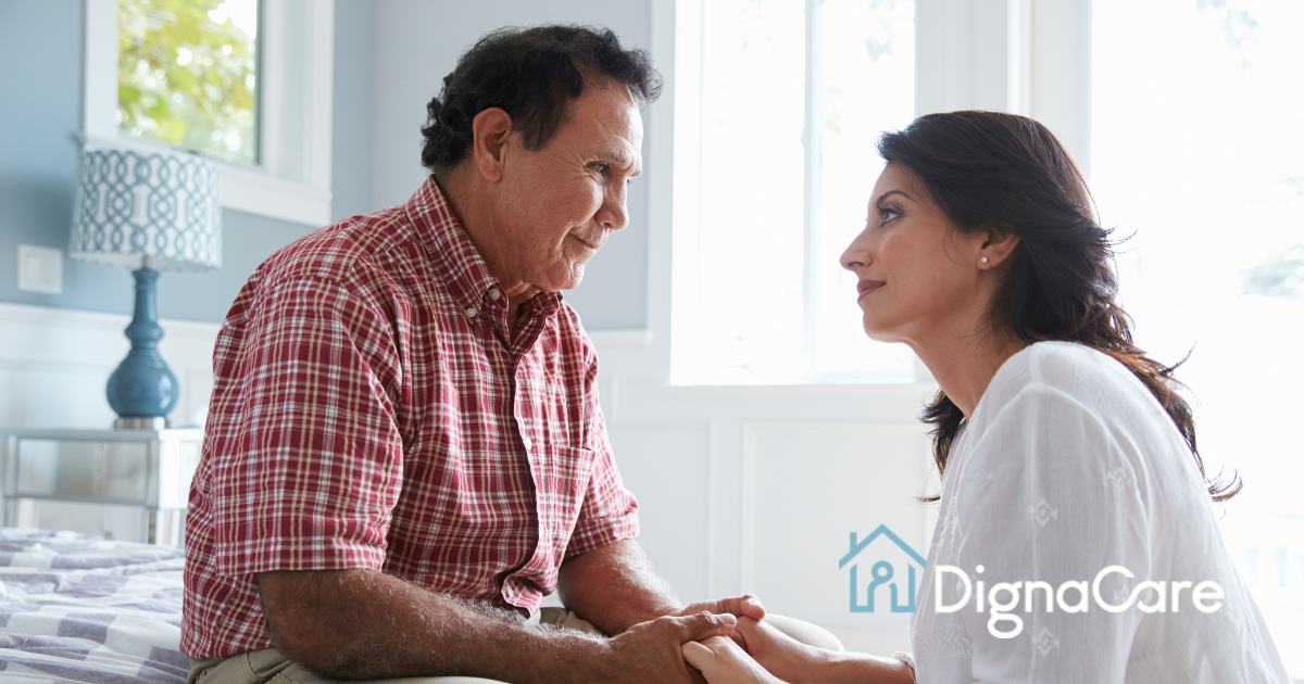 A daughter who is caregiving for her dad who has Alzheimer’s disease, lovingly holds his hands.